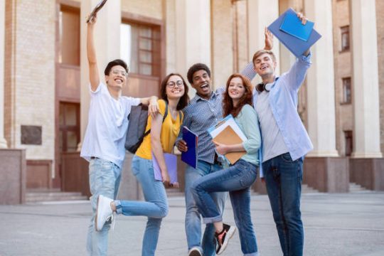 Portrait of excited international high school students raising hands up in the air after passing exam successfully